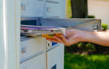 A person's hand pulling a pile of mail out of a mailbox.